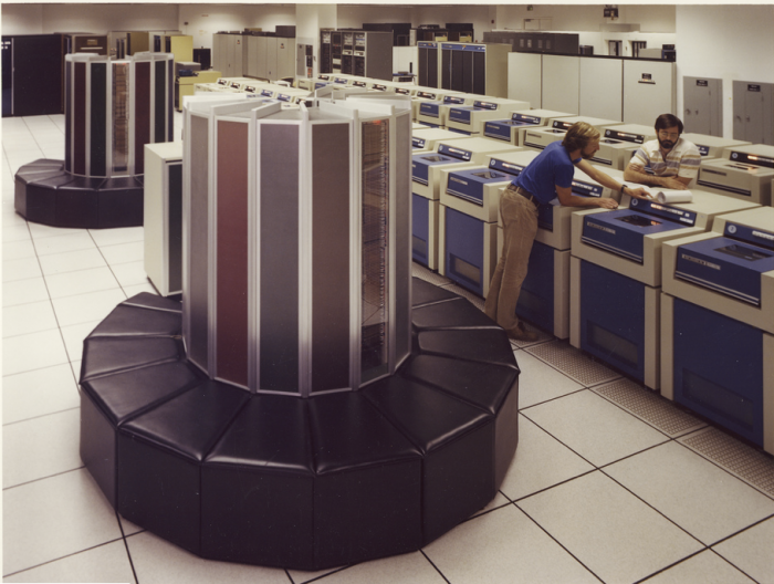 Overhead view of two column-shaped early Cray supercomputers with rows of washing-machine-sized storage units.