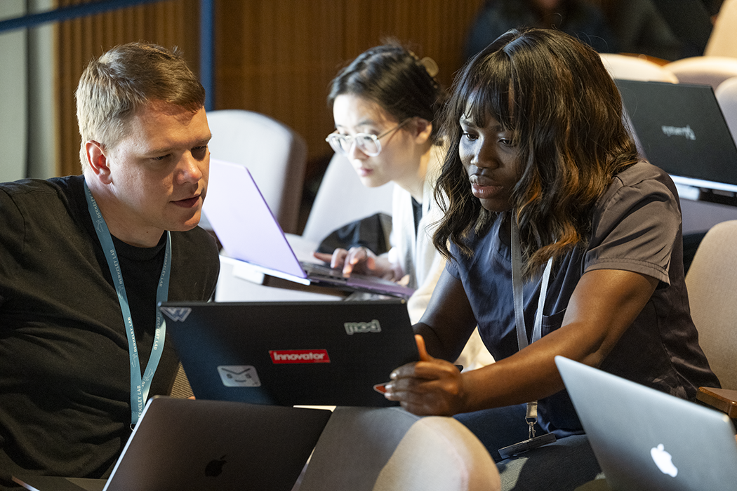 A caucasian man, a Black woman, and an Asian woman discuss computing topics.