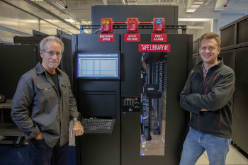 Wayne Hurlbert and Damian Hazen pose in front of the HPSS tape enclosure.